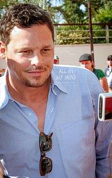 Justin Chambers in a blue shirt looking away from the camera