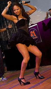 Kat DeLuna dancing onstage in a short, black dress