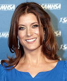 Kate Walsh smiling at the camera in a blue dress