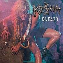 A blond-haired woman rests on a rock wall. She wears tribal clothes: a dark suit, boots and bone ornaments. She has three strips painted across her left eye and a skull, and a long white strip, throughout her left arm. Over her left shoulder the words "Ke$ha" and "Sleazy" are written.