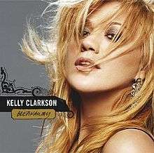 A blonde haired woman with her hair being swept by the wind, in her right, the words "Kelly Clarkson" and "Breakaway" are printed in front of a vector scroll art.