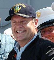 A man wearing a cap smiles broadly.