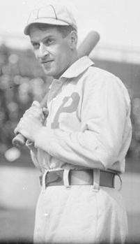 A black-and-white photograph of a man in a white uniform with a striped cap. A "P" is embroidered over the right breast.