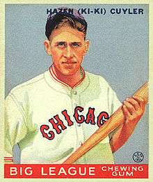 A baseball card of a man holding a baseball bat with both hands while wearing a white baseball jerseys with "Chicago" written across the chest in blue-bordered red letters and a blue cap.