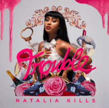 An image of Natalia Kills wearing a white dress, and standing on a grey background, with her hand on her chest. Around Kills, watches, champagne, police cars, roses, handcuffs and other objects. The word "Trouble" appears on the center of the image, and is written in pink-coloured lipstick. The text "Natalia Kills" appears on the bottom of the image. On the upper corners of the image, dripping pink lipstick is shown.