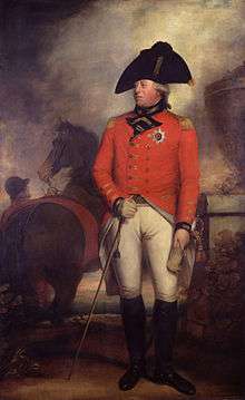 George wearing the red jacket of an 1800 British army general with the star of the Order of the Garter, white breeches, black knee-high boots, and a black bicorne hat. Behind him a groom holds a horse.