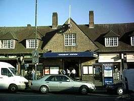 A brown-bricked building with a rectangular, dark blue sign reading "KINGSBURY STATION" in white letters all under a light blue sky