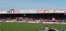 One of the stands of the Bootham Crescent association football ground, with supporters waving flags and a grass field below