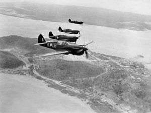 Four single-seat piston-engined fighter aircraft flying in formation