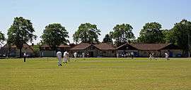 Cricket being played in front of the pavilion at Knowle Cricket Club Ground