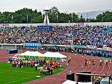 People cheering their teams with colorful flags for track and field games in a stadium