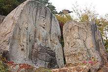 Five Buddhas carved into two natural rocks.