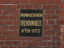 Plaque on a brick wall with inscription: Григорий Константинович Орджоникидзе, 1886-10-28–1937-02-18