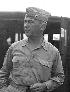 Man in garrison cap and open necked shirt, both sporting sets of three stars.