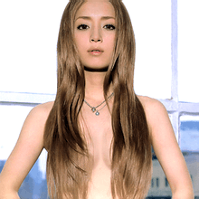 Ayumi Hamasaki shown topless from the upper waist up, looking into the camera, with flowing brown hair covering her chest.