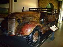 A three-quarter view of a small, four-wheel truck, it has some rust but it largely intact