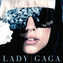 Gaga's face wearing black glasses, whose right side is covered by blue crystals. On the bottom of the left side of the glasses, the word "The Fame" is inscribed in white.