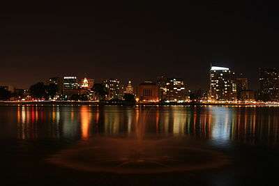 The skyline of a city seen at night from across a lake