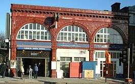 A red-bricked building with a dark blue, rectangular sign reading "LAMBETH NORTH STATION" in white letters all under a light blue sky