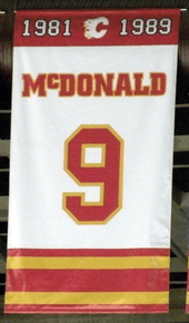 A white, rectangular banner with red and yellow trim at the top and bottom. It reads "1981–1989 McDONALD 9"