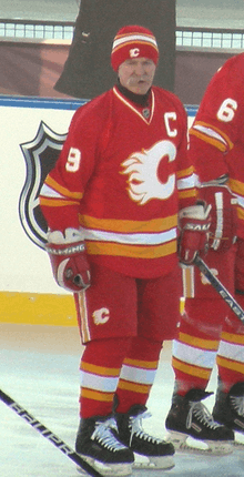 A man skating in a red uniform with white and yellow trim, with a stylized "C" logo on his chest.