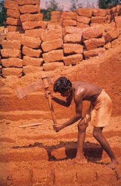 A man is cutting laterite into brickstones in Angadipuram, India.