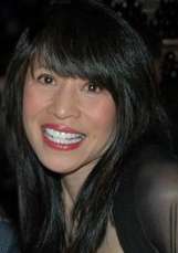 Long-haired Asian-American woman smiling to a camera