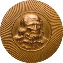 Obverse of a golden medal with the image of Leonardo da Vinci at the center facing slightly to the right.
