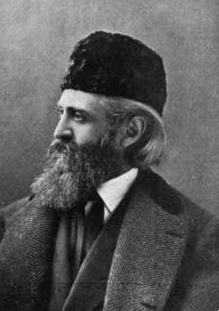 photo in profile of a man with a long beard, wearing a hat and an overcoat