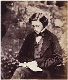 Photographic portrait of Charles Lutwidge Dodgson (Lewis Carroll), seated and holding a book