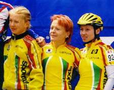 Three young women cyclists, standing in yellow team jerseys