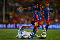 A man named Lionel Messi, wearing FC Barcelona's jersey, dribbling past a player.
