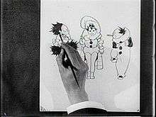 Film still of a hand sketching three cartoon characters.