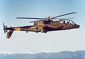 A side view of an AH-56 Cheyenne in hover, a few feet above a helipad.