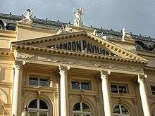 Colour photograph of a neoclassical building with a number of statues on the roof and a decorative façade consisting of four columns topped by a triangular pediment. Letters spelling "London Pavilion" are contained within the tympanum.