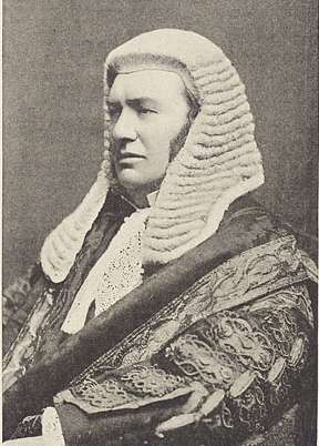A man sitting relaxed and facing the right. He is in full judicial dress, with a wig, suit and heavy robe.