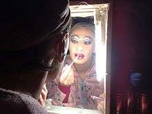 a drag queen putting on lip liner