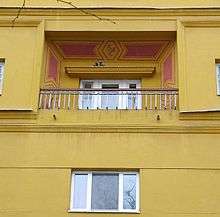 Portion of yellow apartment house with small balcony