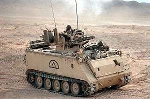 An armored vehicle containing several soldiers in a desert