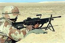A U.S. Marine with an M249 SAW on its bipod manning a foxhole during the Persian Gulf War
