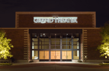 A nighttime photograph of a building that says "Grand Theater" across the front.