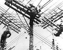 Three men climbing electric poles.