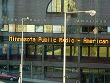 Four stories, with mirror-windows. Electric sign above second floor says MINNESOTA PUBLIC RADIO - AMERICAN.