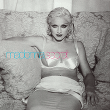 Madonna in a white dress sitting on a sofa and smiling