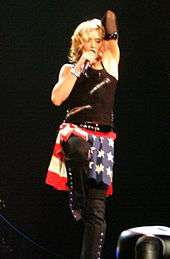 Madonna during a show wearing an all black outfit and an American flag kilt