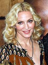1/4 length image of Madonna. She is wearing a blouse and necklace. Her hair is wavy.