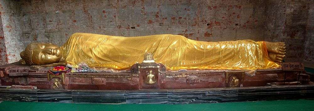 Gold colored statue of Buddha reclining on his right side