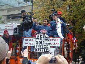 Group of men on a raised platform. One holds a sign that reads "JETER is playing GOLF today" and "THIS IS BETTER!"