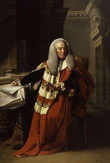 A full-length portrait of an elderly man, seated.  He wears long flowing red and white robes, a long grey wig, and holds a rolled document in his left hand.  His right hand rests on a table littered with documents.  Behind him, the corner of a room, with ornate plaster architrave, is visible.
