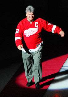 Marcel Dionne walking down a red carpet on ice while wearing a Red Wings jersey